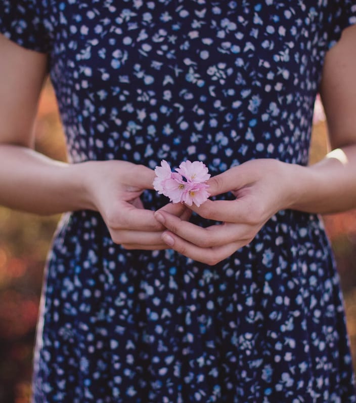Hands gently holding pink blossoms.